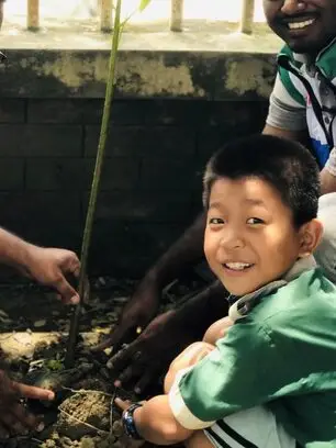 A boy planting a tree with HEART volunteers